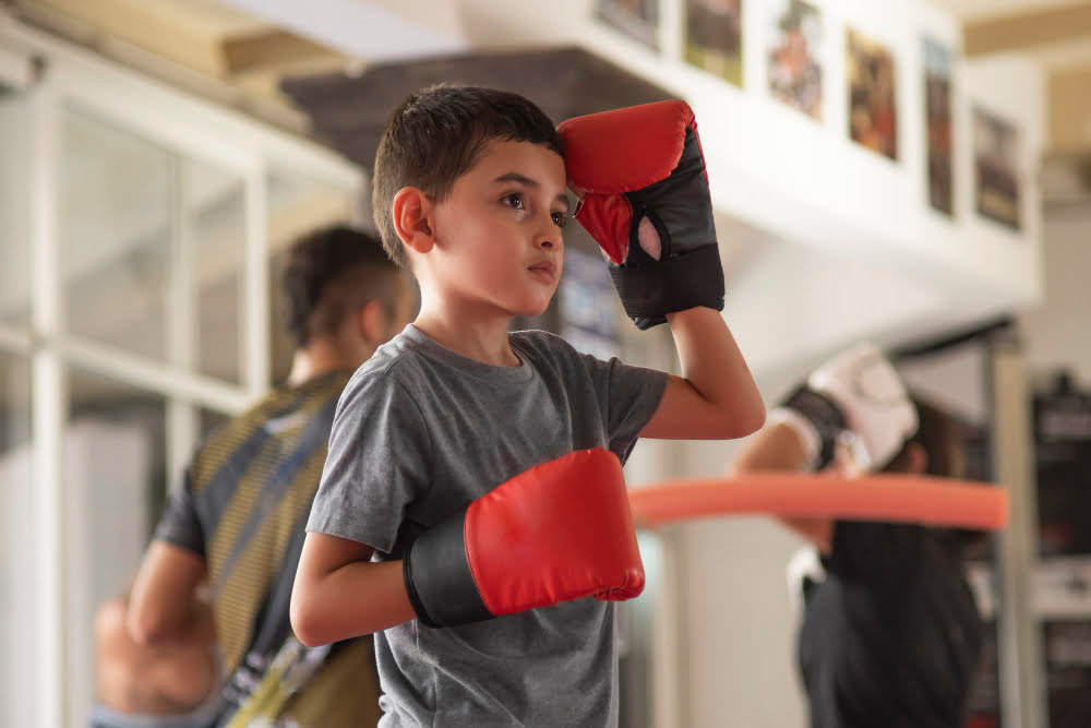 Jonge kickbokser traint met bokshandschoenen in de gym